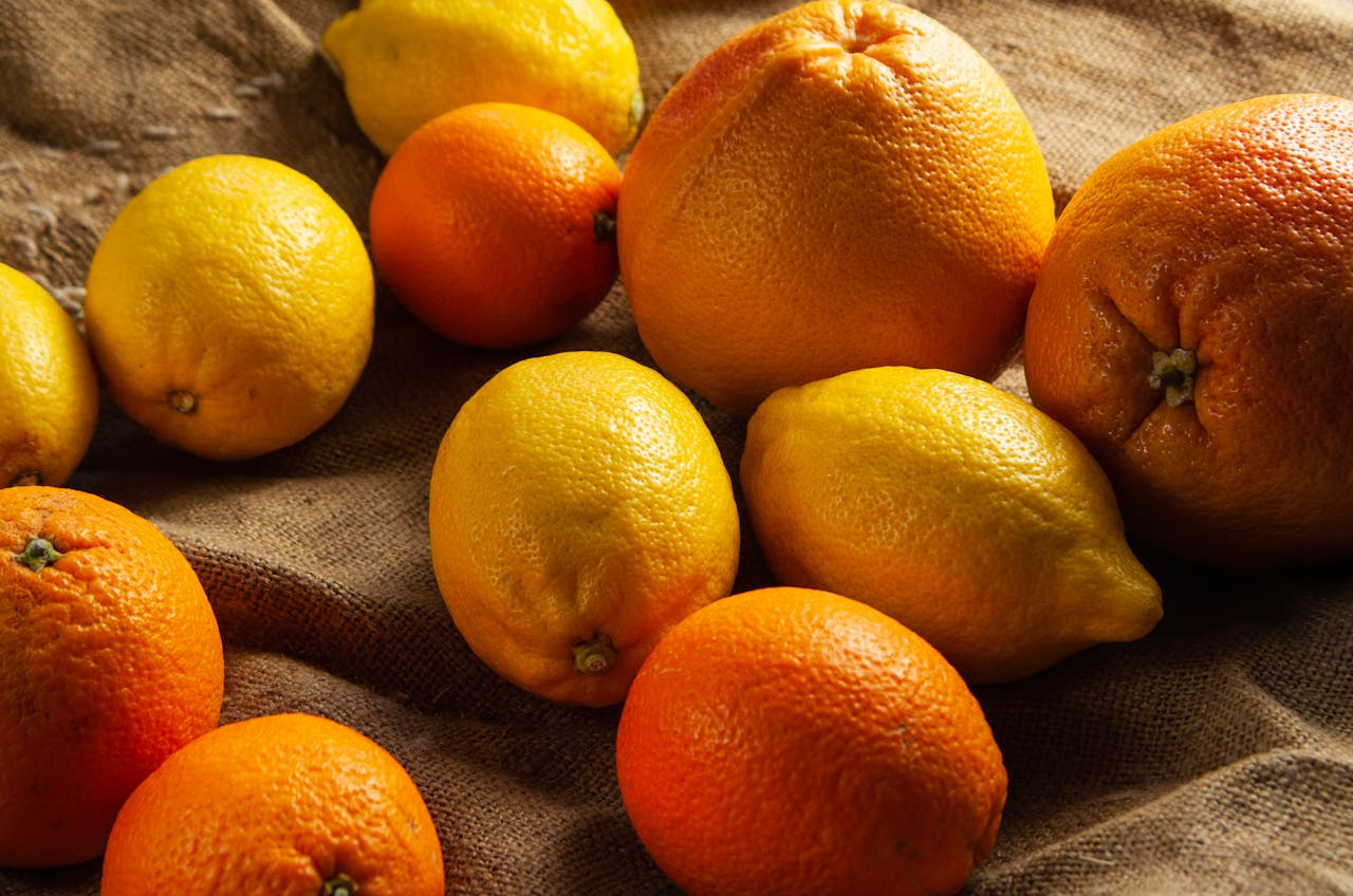 Colorful assortment of lemons and oranges arranged on a textured burlap surface.