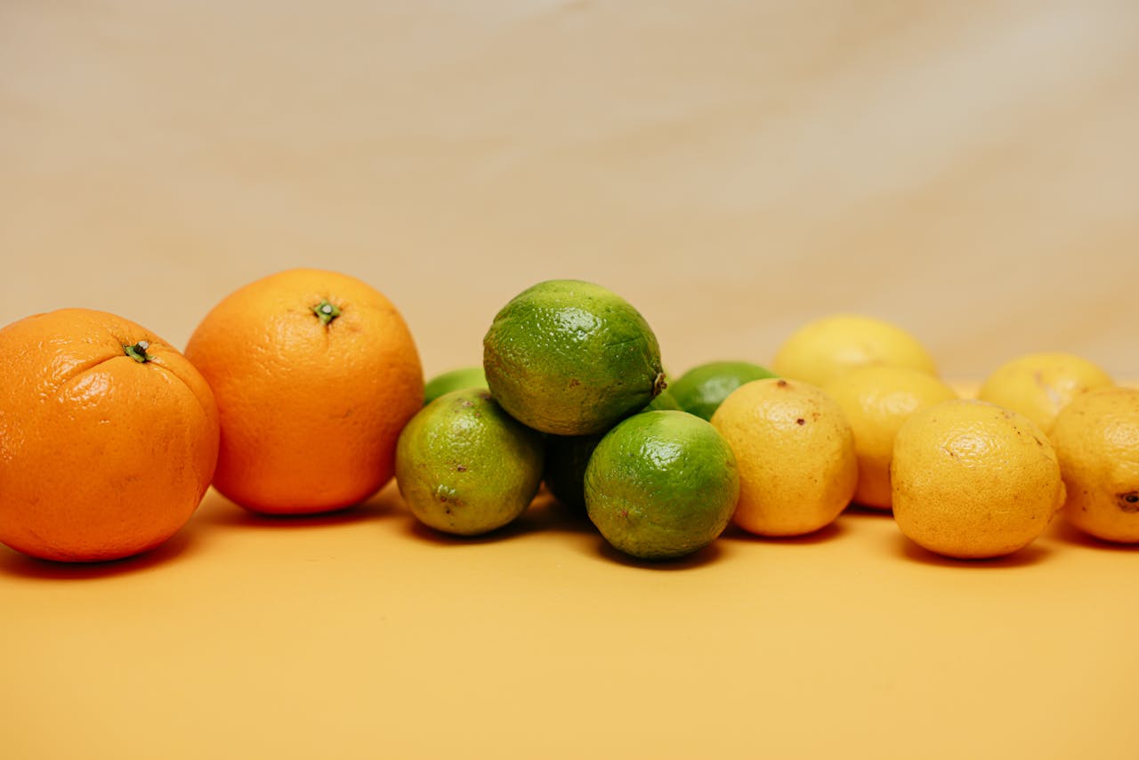 A colorful arrangement of fresh citrus fruits including oranges, limes, and lemons on a warm background.
